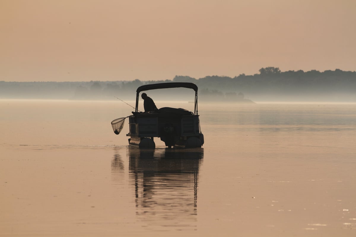 Pontoon boat on lake with evening sunset